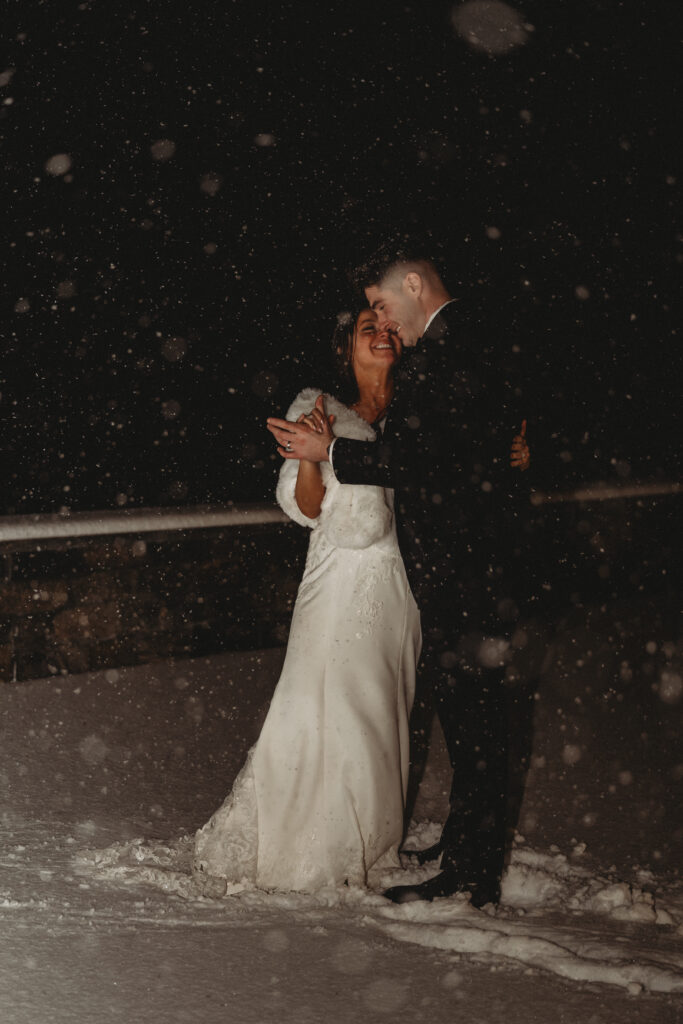 Close up of bride and groom embracing in heavy snowfall during Connecticut winter wedding