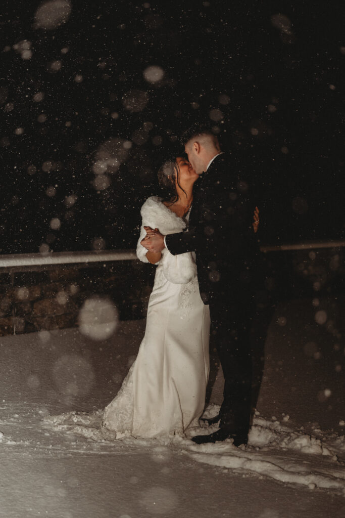 Close up of bride and groom embracing in heavy snowfall during Connecticut winter wedding