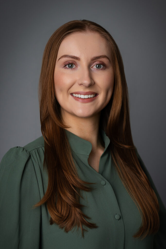 Caroline smiling in a green blouse, capturing an approachable presence that makes a memorable first impression.