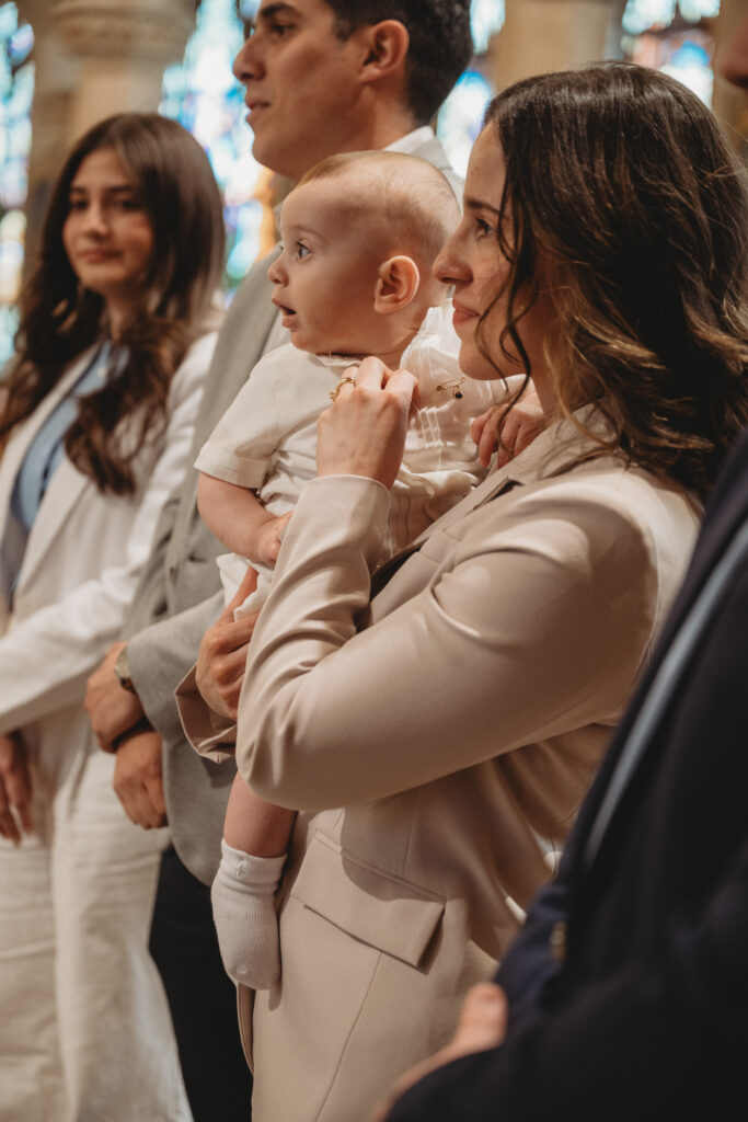 A profile shot of a mother holding her baby during the ceremony, surrounded by family members in a Bristol, CT church.