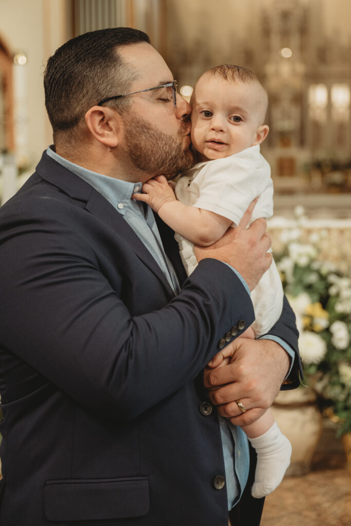 A heartwarming photo of a father kissing his baby boy's cheek, highlighting the "joy and connection" of the Alfano family's special day.