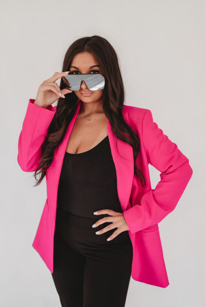 Sarah Khan, founder of BLT, wearing a statement pink blazer and silver sunglasses, posing with confidence during her branding session in North Haven, CT.