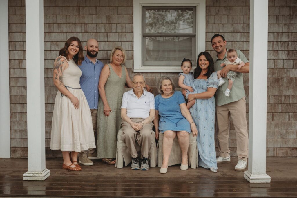 A happy family of four — parents with their young son and daughter — posing together in a lush green garden during a lifestyle family session